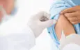 Une personne recevant une injection dans le bras par un agent de santé portant des gants.
