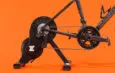 Vélo S-Works monté sur le home-trainer connecté Zwift Hub sur fond orange.