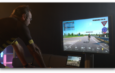 Un cycliste d'intérieur utilise le simulateur virtuel BKOOL affiché sur un grand écran.