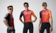 Trois coureurs posent avec le maillot rouge et orange de l'équipe INEOS Grenadiers et un cuissard noir.