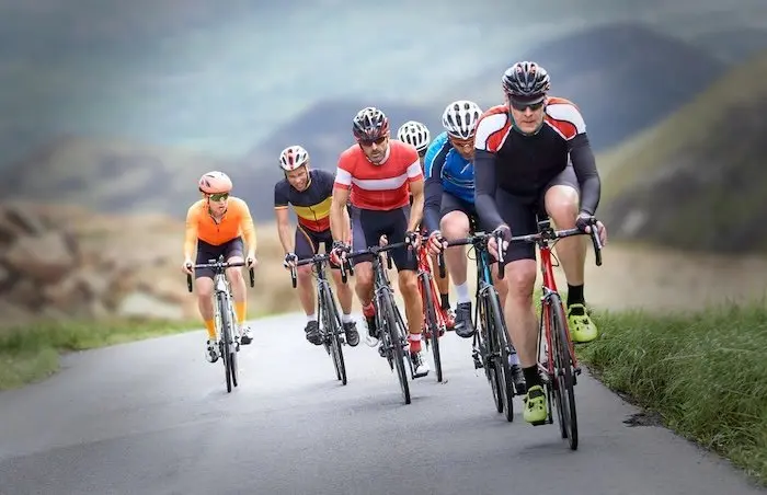 Groupe de cyclistes qui roulent sur une route vallonnée