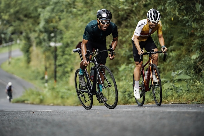 Due ciclisti che sprintano su per una collina