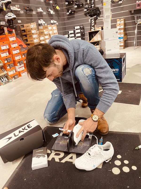 Meccanico che regola le tacchette sotto le scarpe da ciclismo
