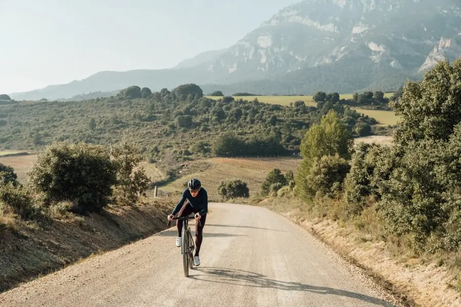 Cycliste en danseuse sur une route de gravel