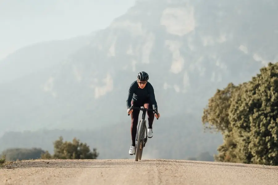 Cycliste sur une route de gravel avec une montagne floue en arrière plan