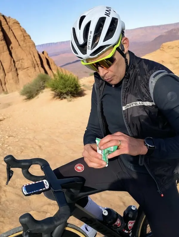 Cycliste en train de se ravitailler, dans un paysage désertique