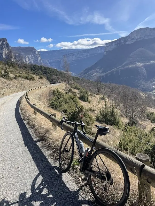 Vélo posé sur une barrière avec paysage de montagne sous le soleil