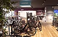 Intérieur d'un magasin de cycles avec de nombreux vélos exposés et un présentoir.