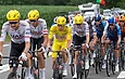 Un groupe de cyclistes professionnels en maillots de l'équipe UAE Emirates roulant en peloton.