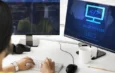 Un codeur travaille sur deux écrans, l'un affichant du code et l'autre le mot ALGORITHM avec une icône.