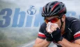 Cycliste casqué portant des lunettes de soleil se mouchant dans un mouchoir.
