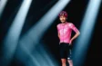 Cycliste portant le maillot rose EF Education et un cuissard noir sous des projecteurs.