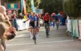 Un cycliste Alpecin franchit la ligne d'arrivée le bras levé, suivi de près par d'autres coureurs.
