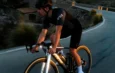 Cycliste sur un vélo de route Cannondale Synapse roulant sur une route de montagne au crépuscule.