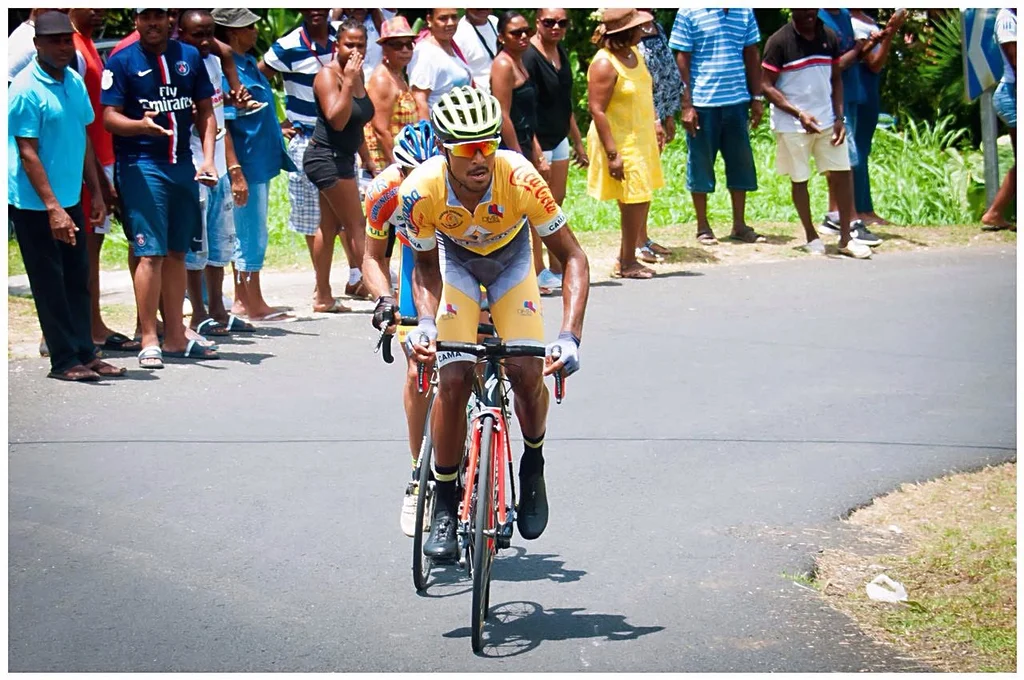 Boris Carène en maillot jaune à l’effort devant le public sur une route de Guadeloupe.
