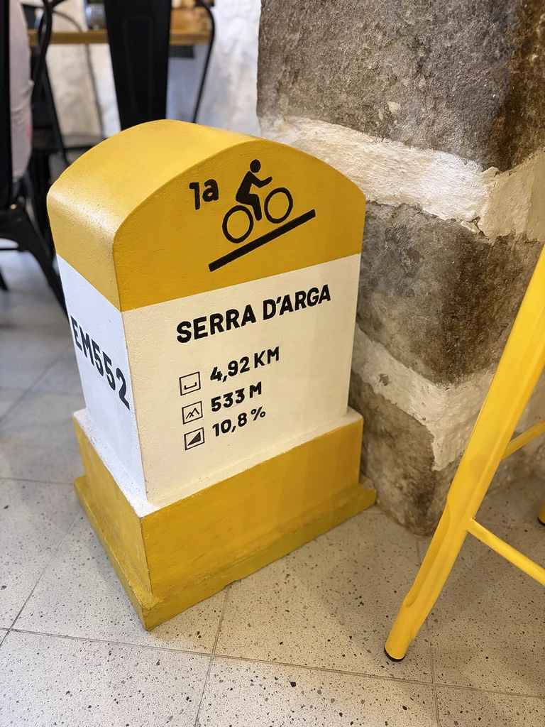 Borne décorative représentant l’ascension de la serra d’Arga à l’intérieur du Peloton Café.