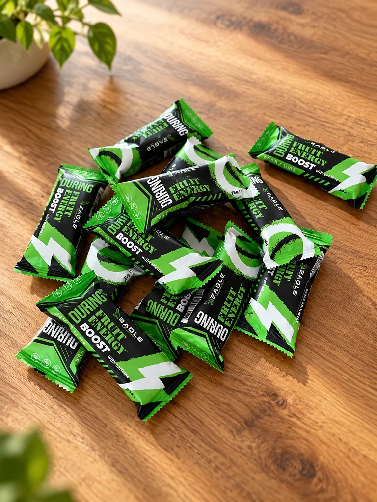 Vue d'ensemble des barres énergétiques Eagle Nutrition Fruit Energy et Fruit Energy BOOST, présentées sur une table en bois. Deux références au parfum poire-citron vert, conçues pour apporter des glucides pendant l'effort, avec un apport supplémentaire de caféine dans la version BOOST.