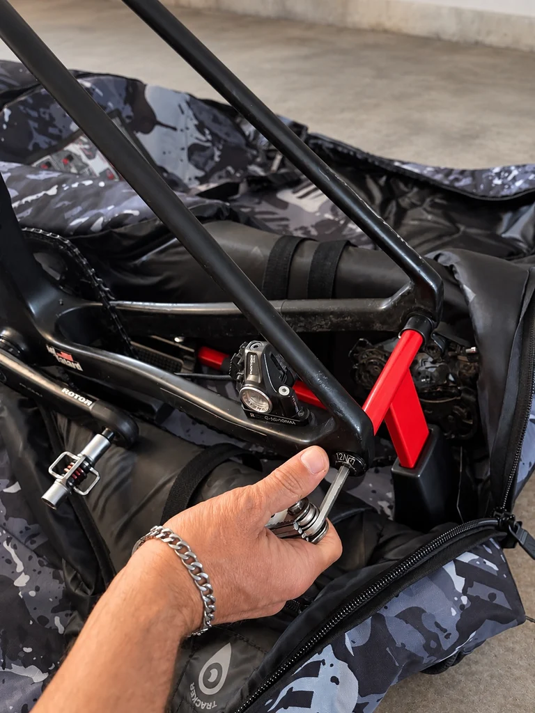 Gros plan sur une opération de serrage avec une clé hexagonale au niveau du cadre Lyti noir, installé sur la structure rouge de maintien de la housse Scicon Aerocomfort 3.1 Gravel.