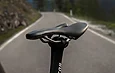 Gros plan sur une selle de vélo SLR montée sur une tige de selle, avec une route en arrière-plan.