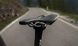 Gros plan sur une selle de vélo SLR montée sur une tige de selle, avec une route en arrière-plan.