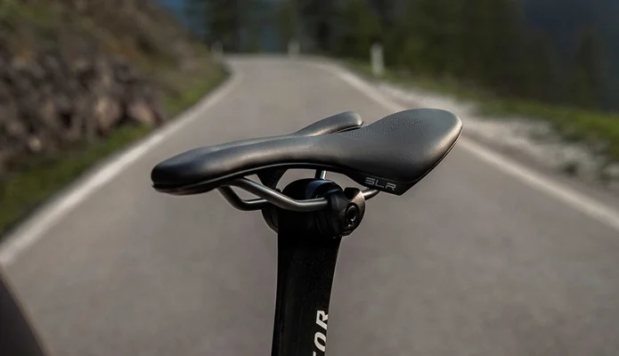 Gros plan sur une selle de vélo SLR montée sur une tige de selle, avec une route en arrière-plan.